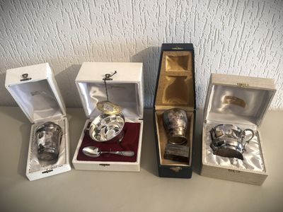 trois objets plaqués argent se trouvent dans une boîte posée sur une table