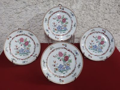 trois assiettes ornées de fleurs, posées sur une nappe rouge
