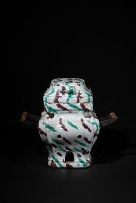 an image of a white vase with a green and brown design on it