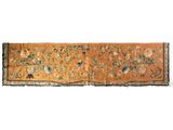 un tapis orange et bleu orné de fleurs et d'oiseaux
