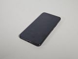 le dos d'un téléphone portable noir posé sur une table blanche