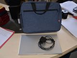 un ordinateur portable et un casque posés sur un bureau, à côté d'un sac