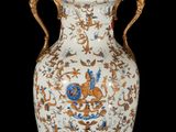 a large vase with a gold handle on a black background