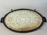 an oval tray with a gold and black design on it