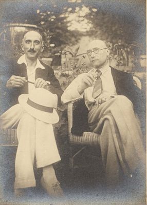 two men sitting on a chair talking to each other in a park