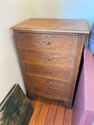 a wooden chest of drawers next to a painting on the floor