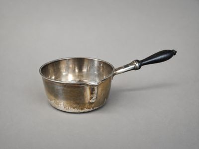 an old silver saucepan with a black handle sitting on a table