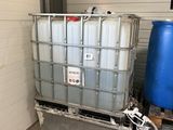 un grand conteneur avec un tuyau d'arrosage à côté d'un fût bleu