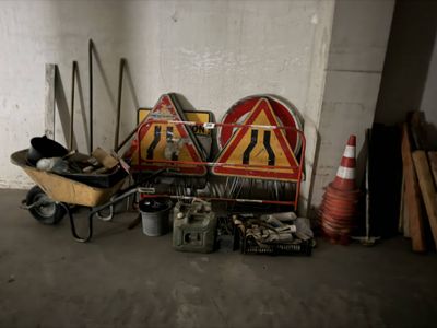 une brouette sur laquelle est accrochée une pancarte, à côté d'un tas de matériel de chantier