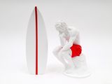 figurine of a man sitting on a surfboard next to a surfboard