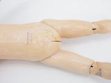a wooden doll laying on a white surface with a needle in it ' s mouth
