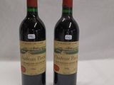 two bottles of red wine sitting next to each other on a table