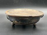 an old metal bowl sitting on top of a black table