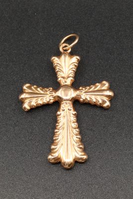 un pendentif en forme de croix dorée sur fond noir