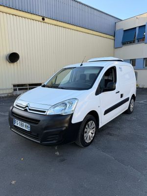 La camionnette blanche est garée sur un parking devant un immeuble.