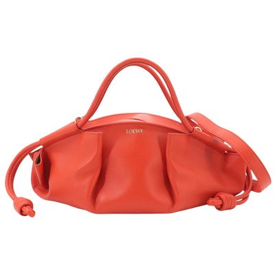 a red handbag with a long strap and two handles