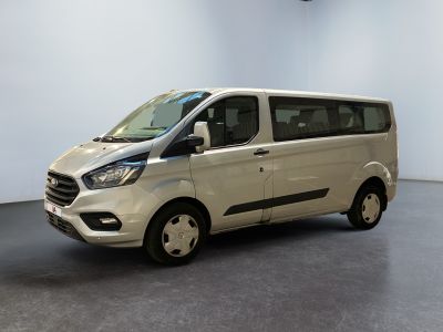 La camionnette blanche est garée dans une grande pièce au sol noir.