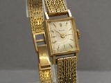 an image of a gold wrist watch on a clear display stand