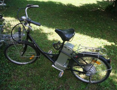 un vélo garé dans l'herbe, avec un panier à l'arrière