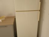 a white refrigerator in a small room with a wooden floor