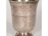 une tasse en argent antique avec un motif floral sur le bord