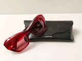 des lunettes de soleil rouges posées sur un étui noir, sur une surface blanche