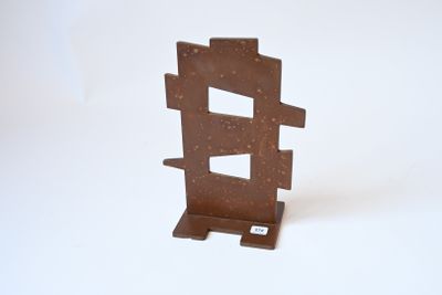 une petite sculpture en métal posée sur une surface blanche
