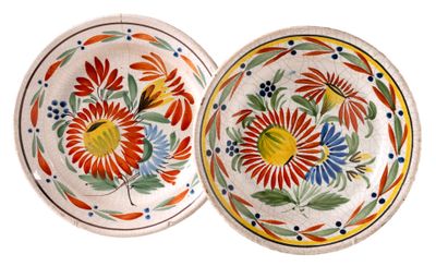 two plates with colorful designs on them are sitting on a white surface