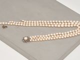 un gros plan d'un collier de perles blanches posé sur une surface grise