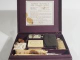 an open box containing a bottle of alcohol, a cigarette, a cigarette case, and other items