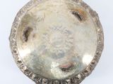 an old silver plate on a white surface with a white background