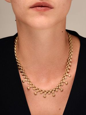 a woman wearing a gold chain necklace and black top