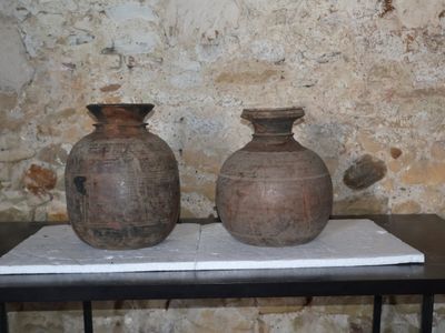 deux vases posés sur une table devant un mur de briques
