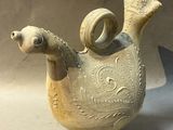 a small vase with a bird on it on a table