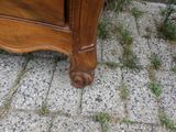 une commode en bois posée sur un sol en pavés