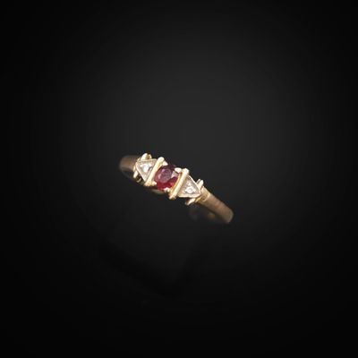 a close up of a gold ring with a red stone