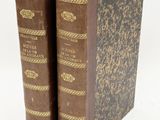 two old books sitting on top of each other on a white surface