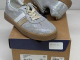 silver glittered sneakers with white laces on top of a cardboard box