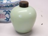a white vase with a brown lid next to a blue and white vase