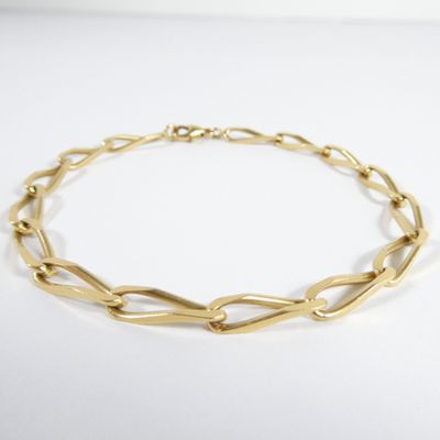 gros plan d'un bracelet en chaîne en or sur une surface blanche
