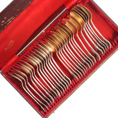 des couverts dans une boîte rouge posée sur une surface blanche recouverte d'un tissu rouge