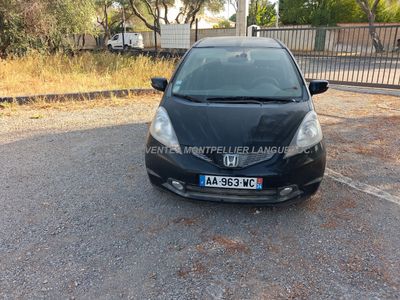 the black car is parked in the parking lot next to a fence