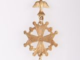 a close up of a gold cross with a bird on it