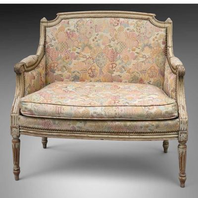 un fauteuil rembourré dont le dossier est orné d'un motif floral