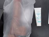 a plastic bag with a foot in it next to a bottle of lotion and a toothbrush