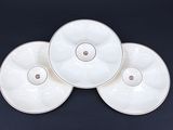 trois assiettes blanches aux bords dorés reposent sur une surface noire