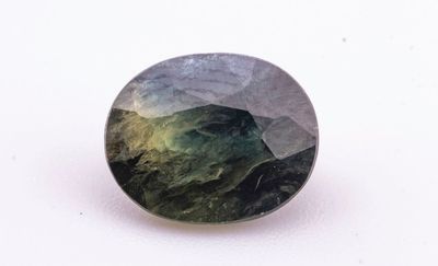 un gros plan d'une pierre verte et noire posée sur une surface blanche