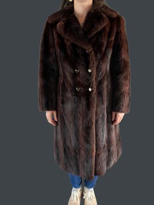 a woman in a brown fur coat standing on a gray background