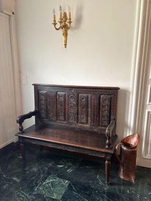 un banc en bois dans un coin d'une pièce où se trouve un lustre