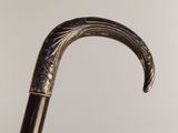 close up of a walking stick with a carved handle against a white background